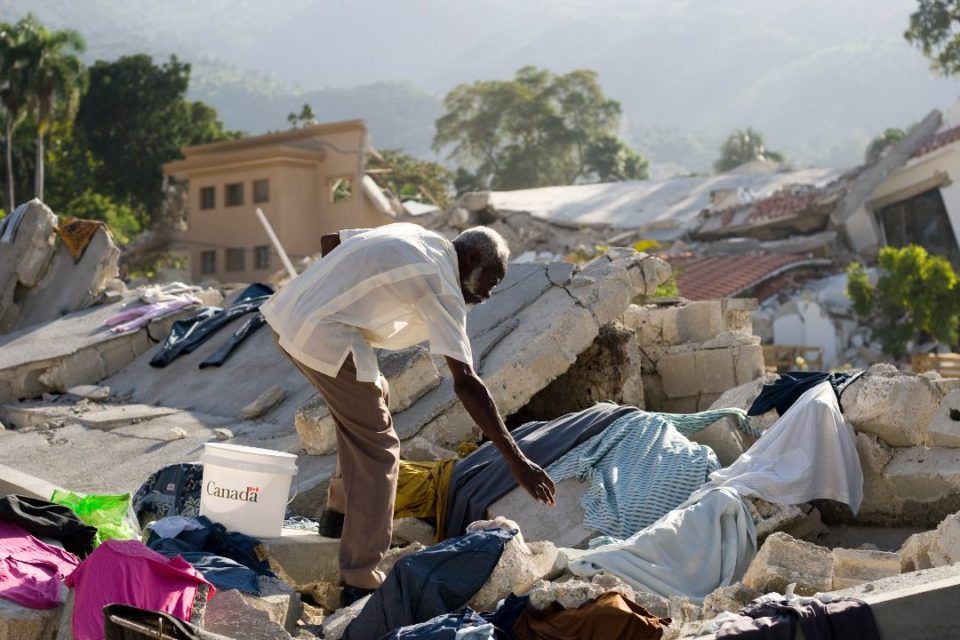 Man searches for belongings amongst rubble