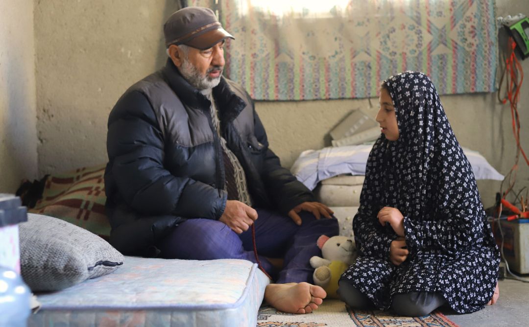 Father and daughter sitting inside an apartment damaged by the Turkey-Syria earthquake.