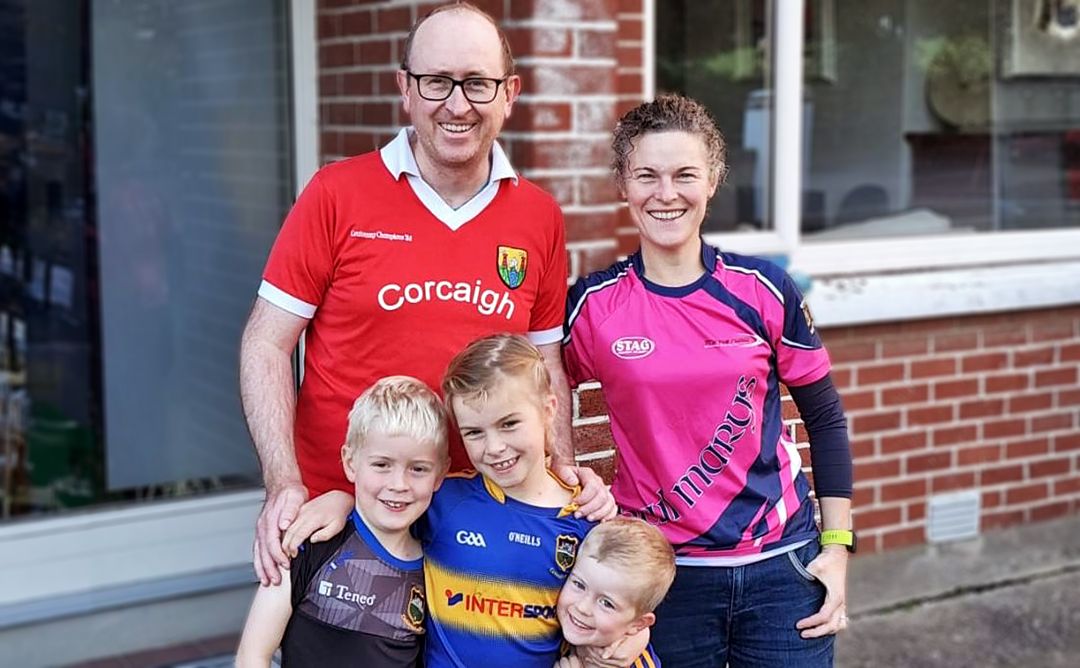 Smiling family (father and mother with their three children) wearing sports jerseys.