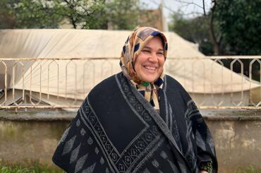 Syrian single mother Fatima stands smiling in Türkiye displacement camp