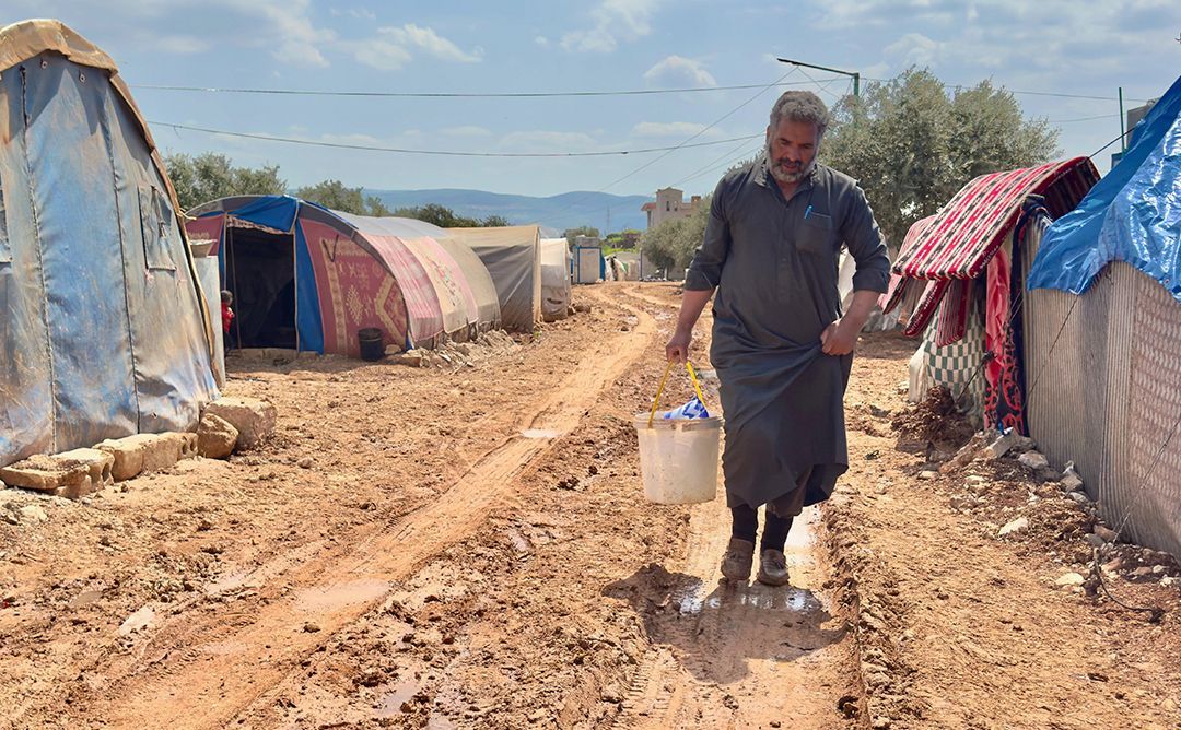 Syria_Relief-IV_WASH_Hussein-carrying-water_DE Hussein trägt Wasser, das er von einem Wasser-LKW gekauft hat, zum Zelt seiner Familie im Al-Wadah-Lager.