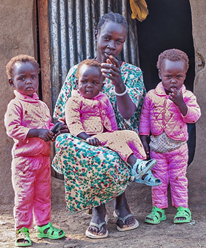 GOAL Ethiopia_Malnutrition_Nyakan_ACQ_RG A mother sitting outside her house in a village in Ethiopia with her three toddler triplets