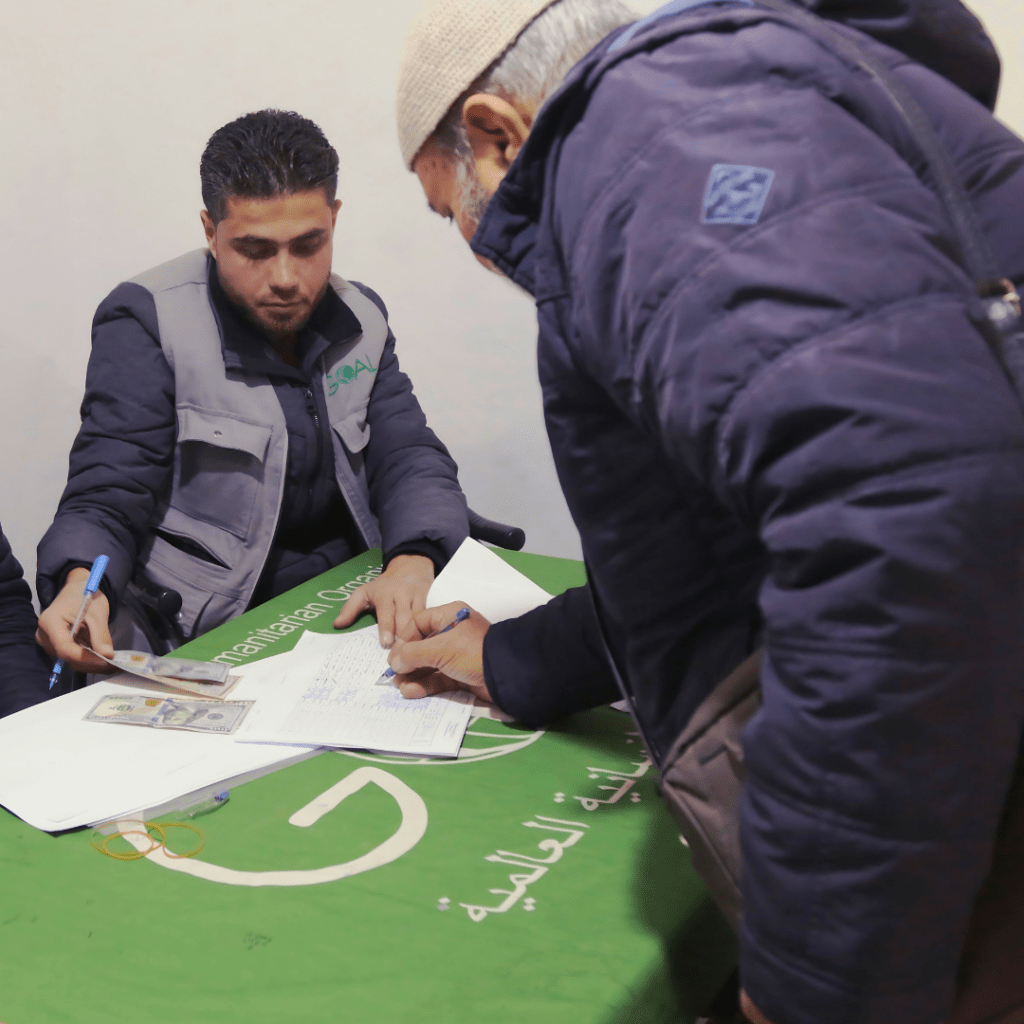 Suleiman receiving cash assistance at the GOAL winter aid distribution centre in Sijo Village.