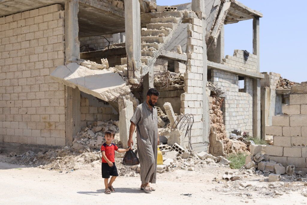 Ahmed Al-Ibrahim -45 years old- with his 4-year-old son Omar, walking in the streets of Haysh, southern Idlib, after purchasing groceries with GOAL's cash assistance they received.
