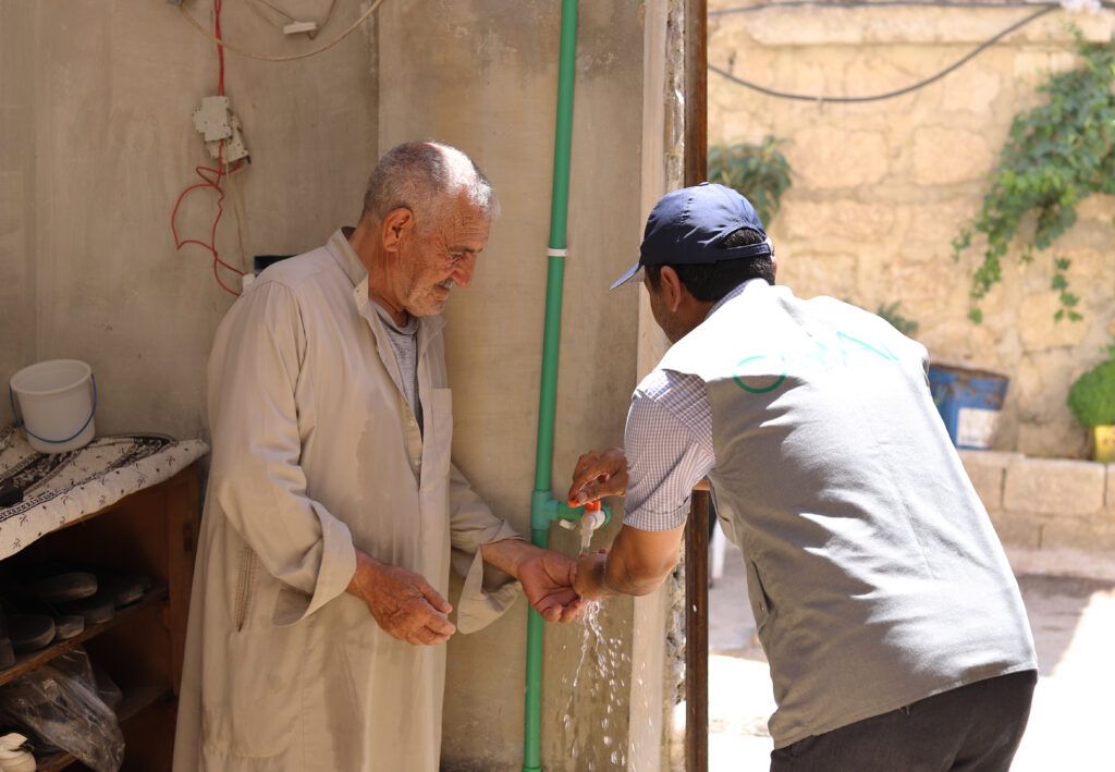 Engineer Khaled Al-Kilay with Mohammads’ home, checking the water tap in rural western Aleppo.