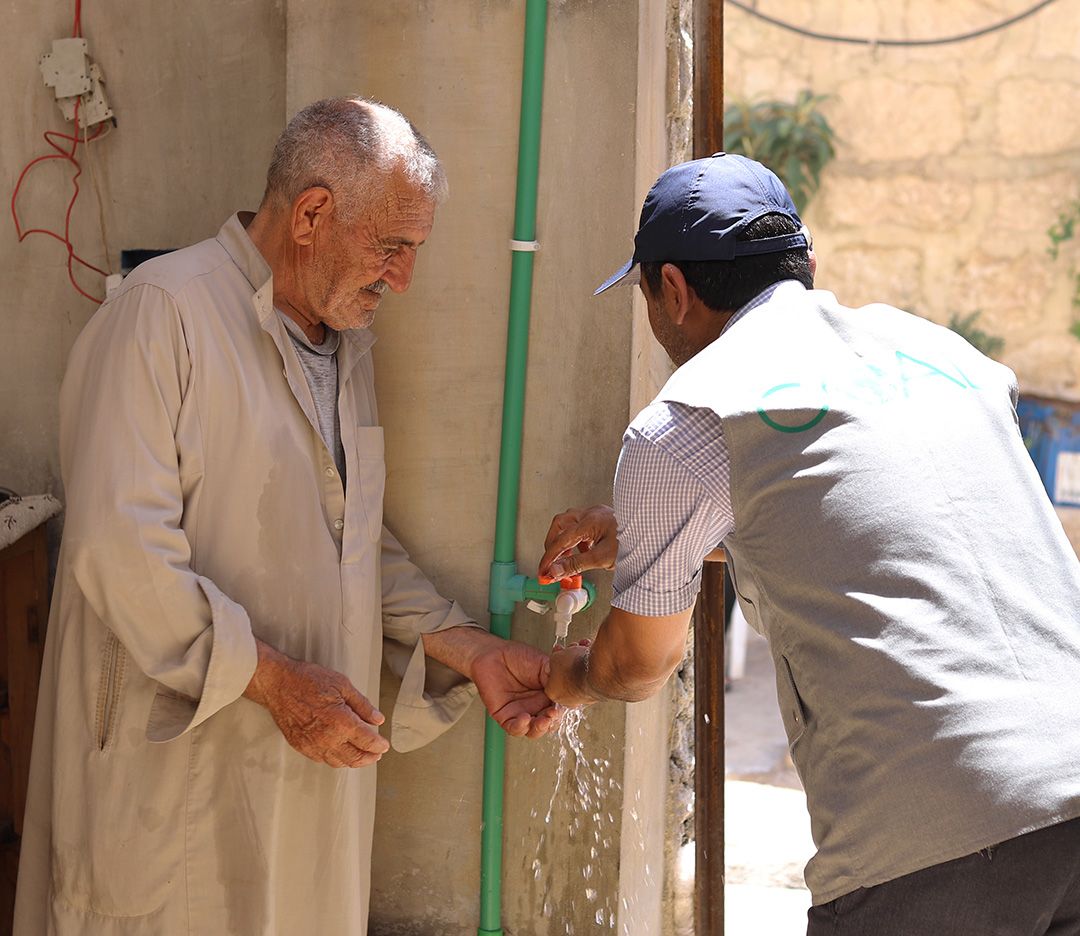 GOAL Engineer Khaled Al-Kilay checks the water tap in Mohammads’ home