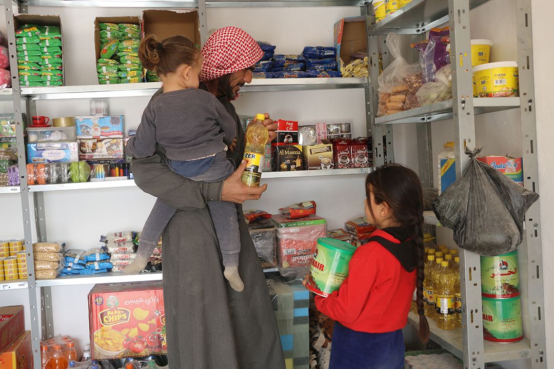 Ali and his granddaughters shop for essential supplies with GOAL's cash assistance